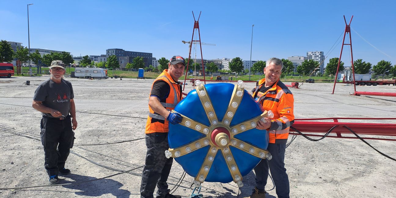 Die Mitarbeiter des Münchner Circus Krone Lorenzo Carnivali (links) und Robert Fossit (rechts) präsentieren die Krone, die ab Montagmorgen das 16 Meter hohe Zirkuszelt auf dem Festplatz Flugfeld zieren wird.