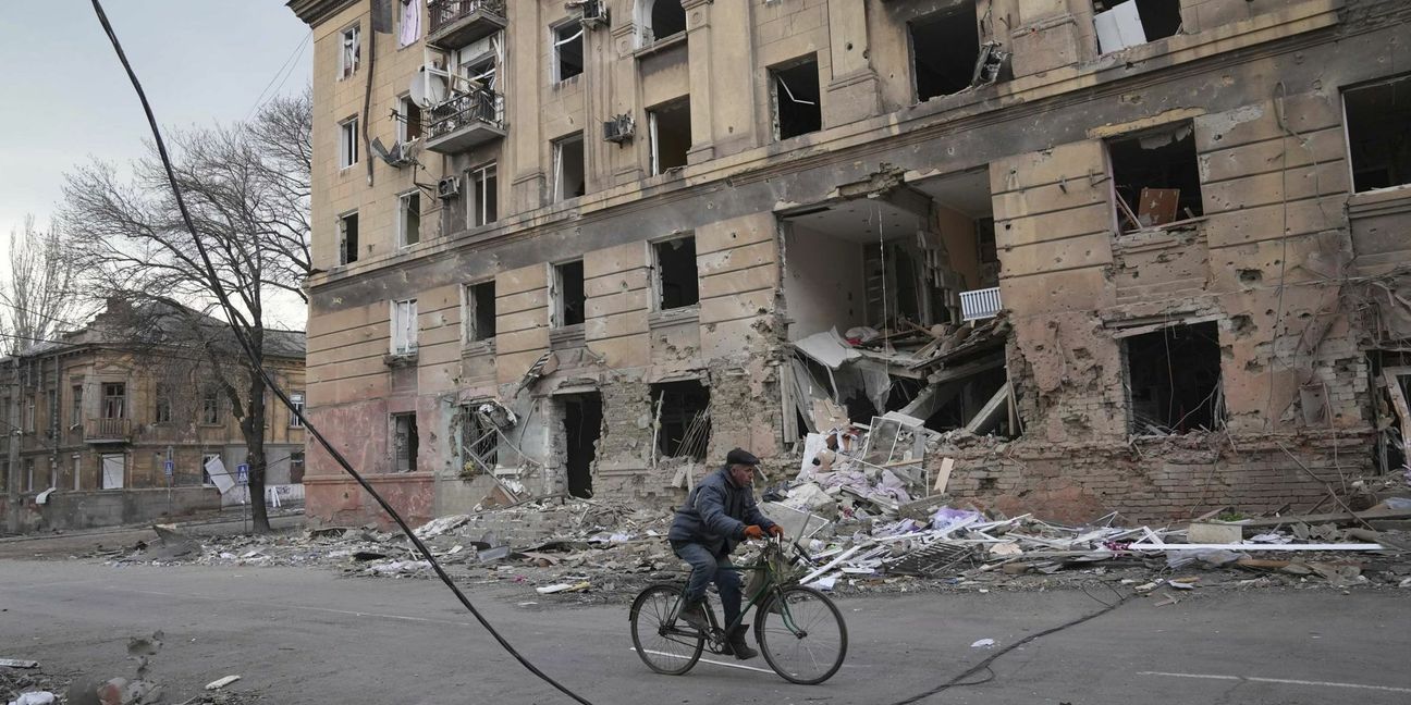 Ein Mann fährt  mit dem  Rad durch das zerstörte Mariupol.