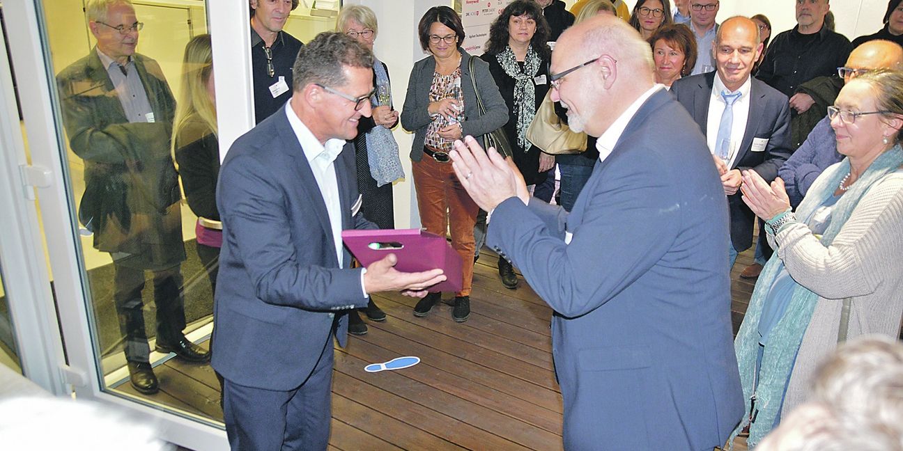 Weil der Stadts Beigeordneter Jürgen Katz (im Vordergrund, rechts) bedankt sich mit einem kleinen Geschenk und viel Beifall bei Wolftechnik-Geschäftsführer Peter Krause (vorne links) dafür, dass er bei der Türöffner-Veranstaltung in die Rolle des Gastgebers geschlüpft ist. Bild: Reichert