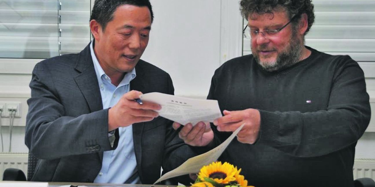 Professor Guangming Li (links) und Armin Kienle nach der Unterzeichnung des Kooperationsvertrags beim Austausch der Urkunden. Bild: Reichert