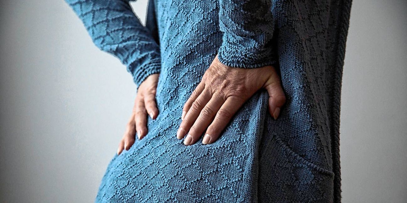 Eine Frau hält sich in einer Physiotherapiepraxis die Hände auf Höhe der Lendenwirbel in den Rücken. Frauen in Deutschland leiden laut einer Befragung des Robert Koch-Instituts (RKI) häufiger an Rücken- und Nackenschmerzen als Männer und haben mehr Schmerzattacken.