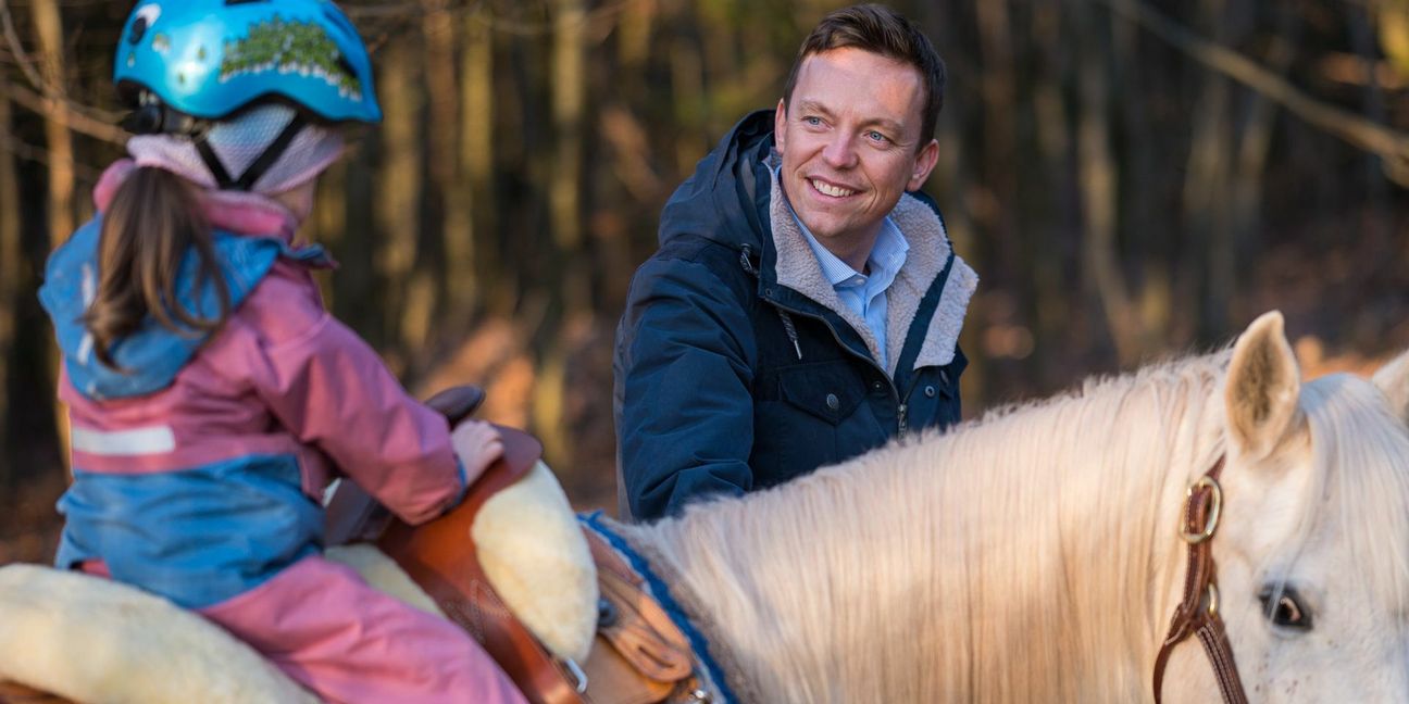 Der saarländische Ministerpräsident Tobias Hans CDU) führt ein Pferd, auf dem eine seiner Töchter sitzt.