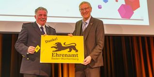 Landrat Roland Bernhard (rechts) übergibt die erste Ehrenamtskarte an den Vorsitzenden des Kreisfeuerwehrverbandes Böblingen Markus Priesching. Bild: Dettenmeyer