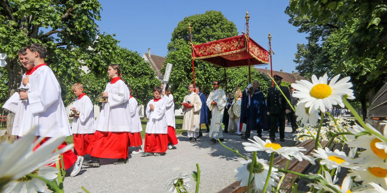 Unter einem Stoffbaldachin wird die Monstranz während der Fronleichnamsprozession am 8. Juni 2023 durch die Straßen des Dorfes Obermarchtal  getragen.