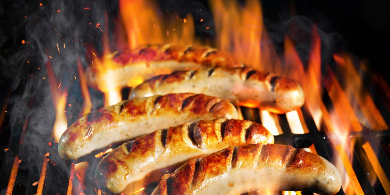 Grilled sausage on the flaming grill with smoke